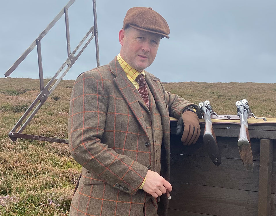 Waiting for the grouse to start moving, traditionally attired in a Massy-Birch tweed suit.